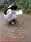 A Girl Learning Rangoli by Looking at a Book